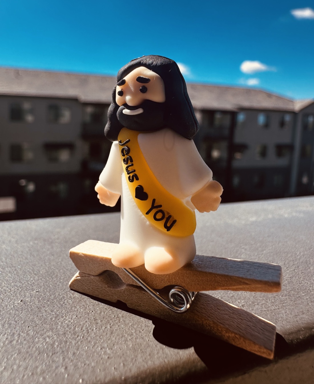 A yellow sash Clip On Jesus close up on a wooden clothespin